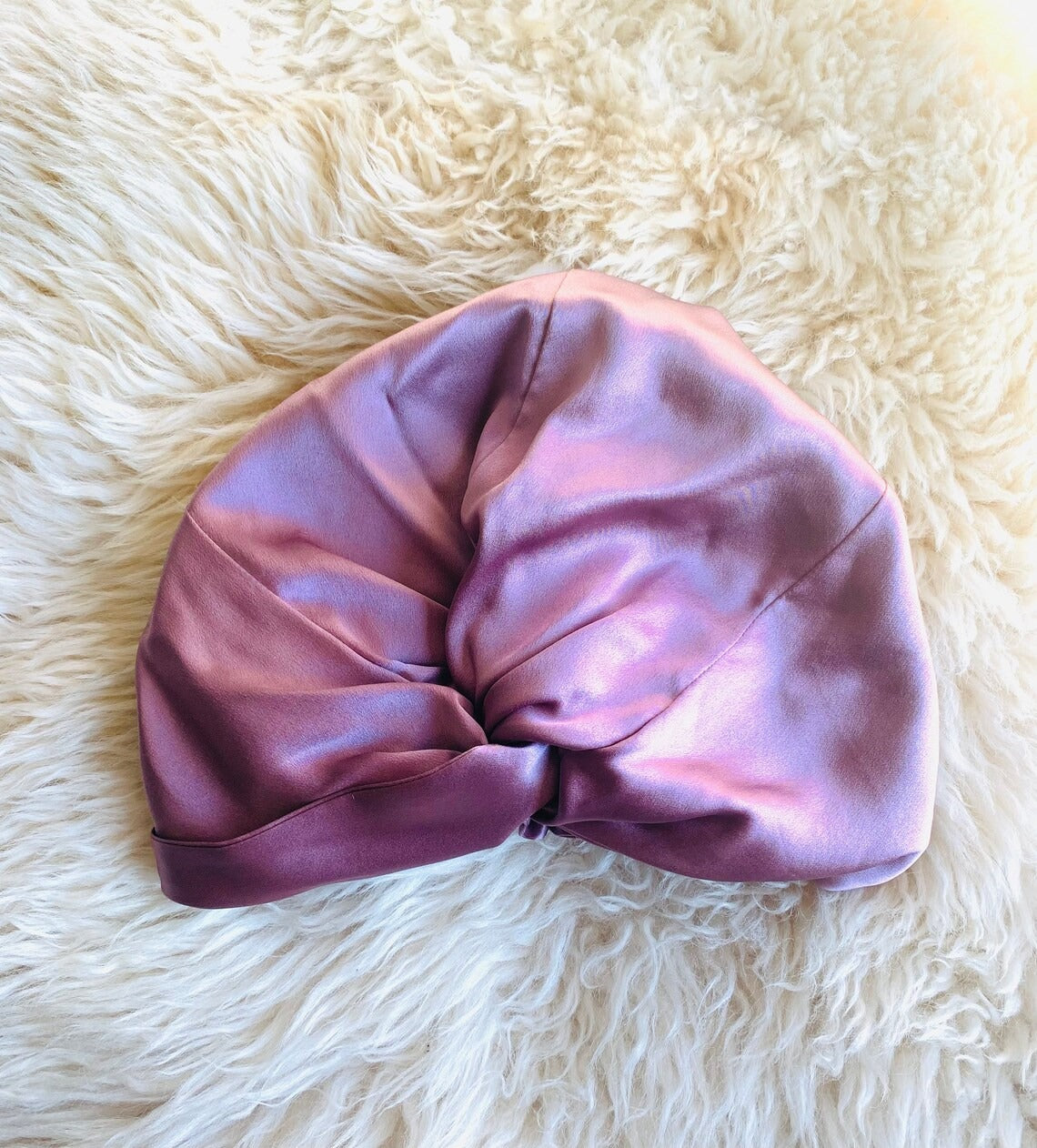 Pink satin bonnet on a white fluffy surface